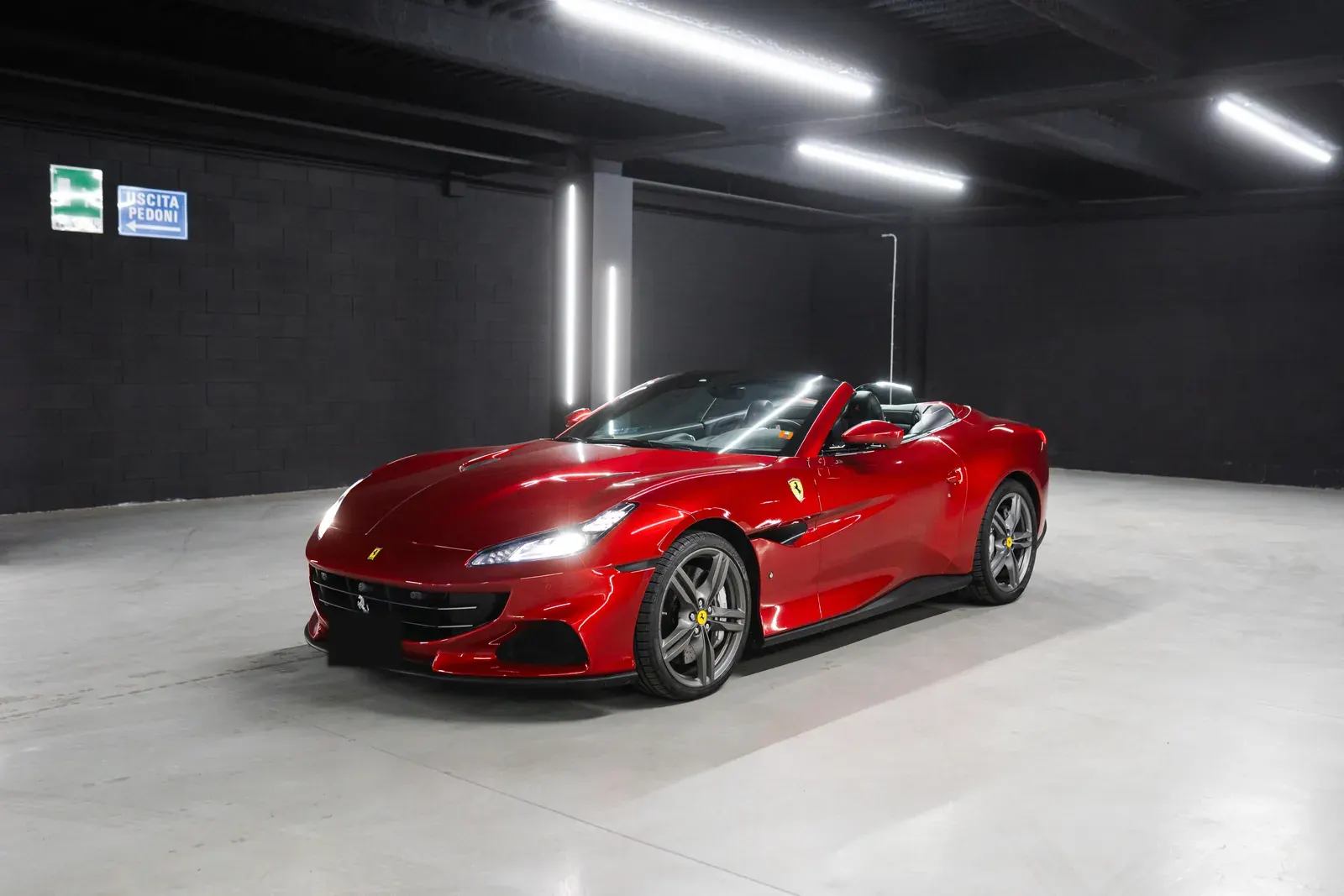 Ferrari rossa decappottabile con il tetto aperto, nel garage di Rial Rent